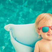 Funny baby boy on summer vacation. Child having fun in swimming pool